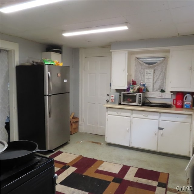 kitchen with stainless steel fridge and white cabinetry