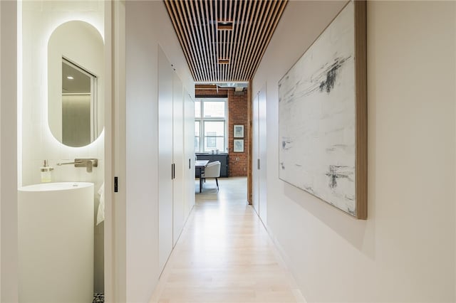 hallway with light hardwood / wood-style floors and brick wall