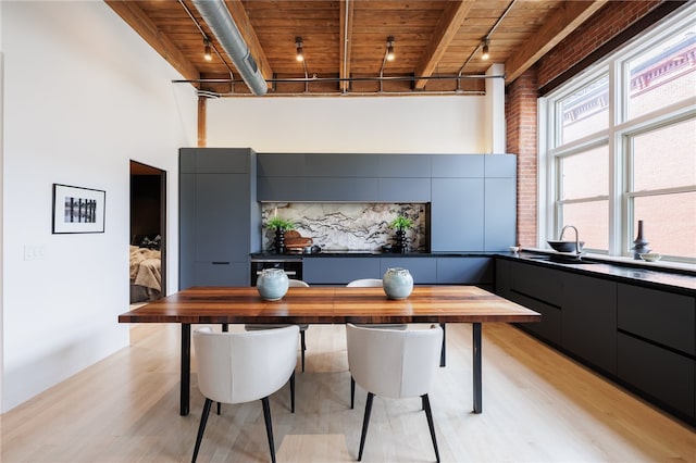 office area with beam ceiling, light hardwood / wood-style floors, wood ceiling, sink, and a high ceiling