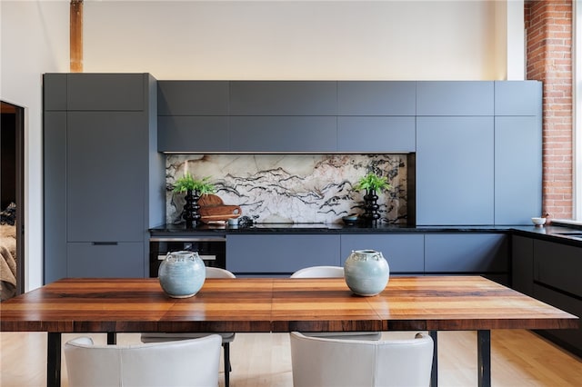 interior space featuring light hardwood / wood-style flooring, backsplash, gray cabinetry, and butcher block countertops