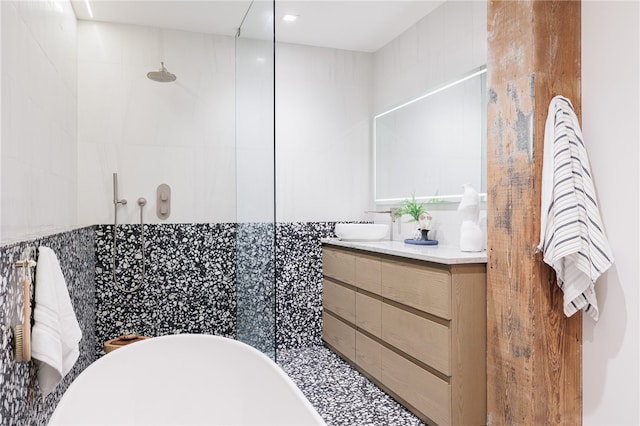 bathroom featuring tile walls, independent shower and bath, and vanity