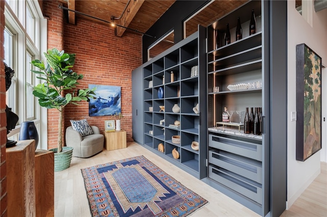 sitting room featuring wood ceiling, brick wall, beamed ceiling, and light wood-type flooring