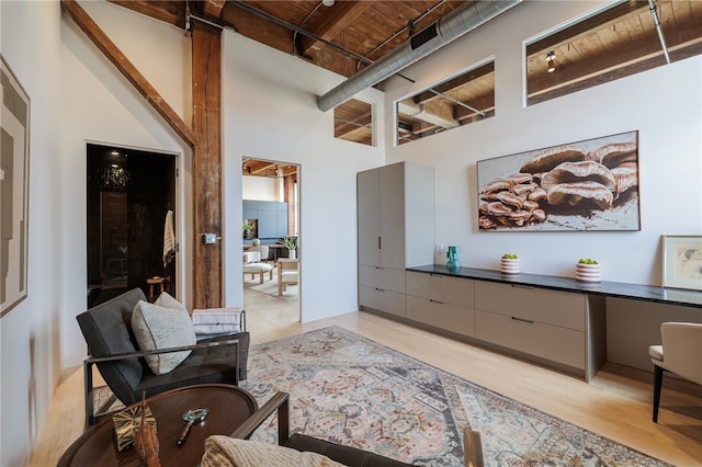 living room featuring light hardwood / wood-style flooring, wood ceiling, and a towering ceiling