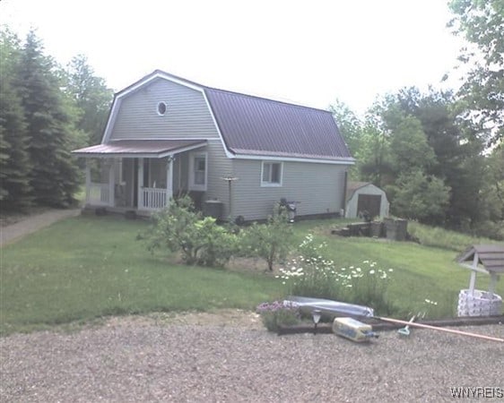 view of front facade featuring covered porch, a storage shed, and a front lawn