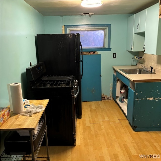 kitchen featuring black appliances, sink, backsplash, white cabinetry, and light hardwood / wood-style flooring