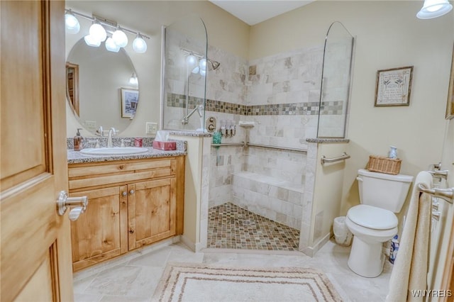 bathroom with a tile shower, vanity, and toilet