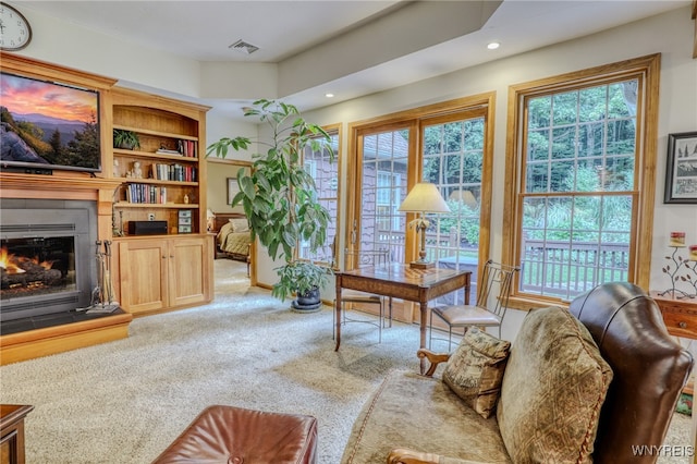 living area featuring carpet and a tiled fireplace