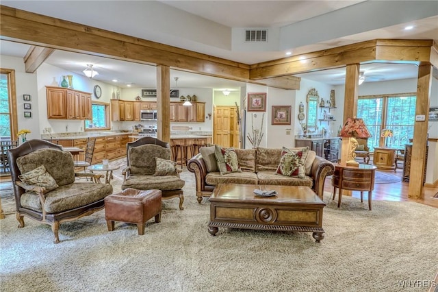 carpeted living room with beam ceiling, a wealth of natural light, and ceiling fan