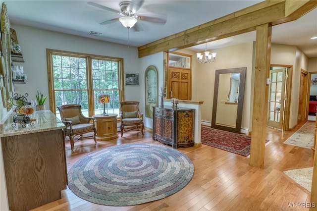 living area with ceiling fan with notable chandelier and light hardwood / wood-style floors