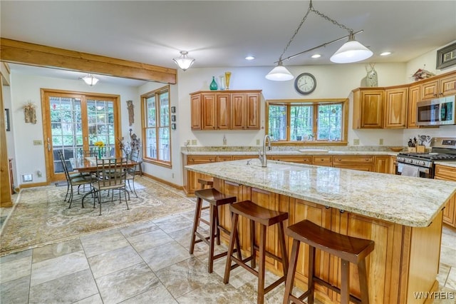 kitchen with a kitchen breakfast bar, a kitchen island with sink, sink, and appliances with stainless steel finishes