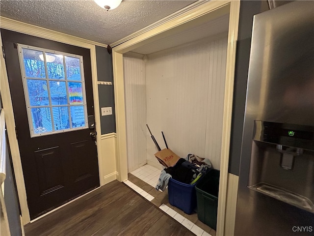 entryway with a textured ceiling, ornamental molding, and hardwood / wood-style floors