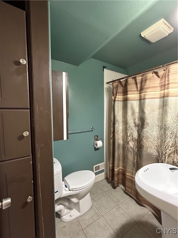 bathroom featuring toilet, curtained shower, and tile patterned flooring