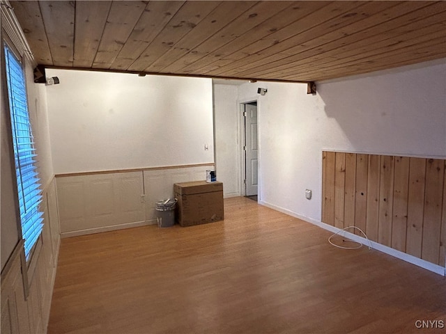 empty room featuring wood ceiling, wood walls, and light hardwood / wood-style flooring