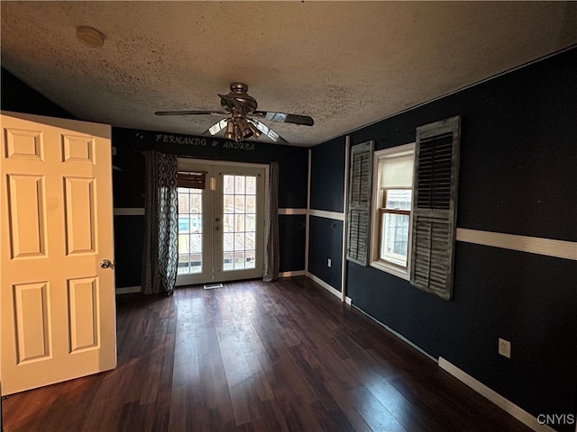 empty room featuring french doors, dark hardwood / wood-style floors, a textured ceiling, and ceiling fan