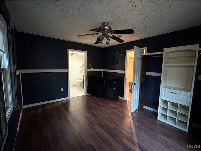 unfurnished bedroom featuring ensuite bath, ceiling fan, a textured ceiling, and dark hardwood / wood-style flooring