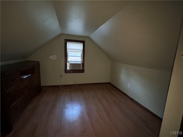 additional living space featuring cooling unit, hardwood / wood-style floors, and vaulted ceiling