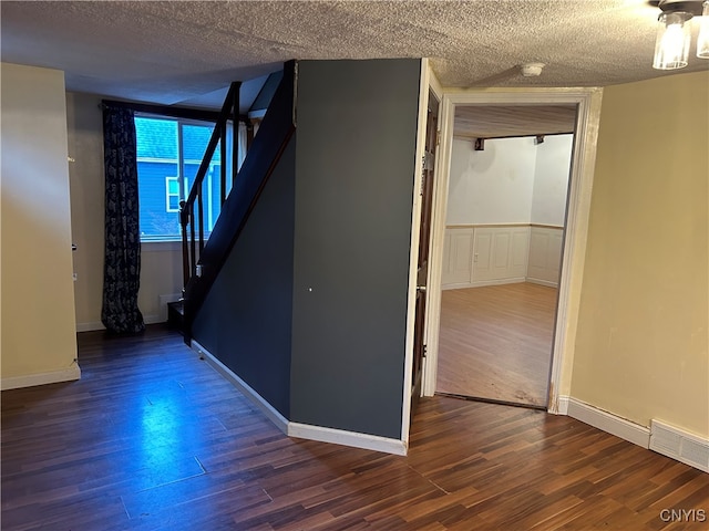 hall with dark wood-type flooring and a textured ceiling