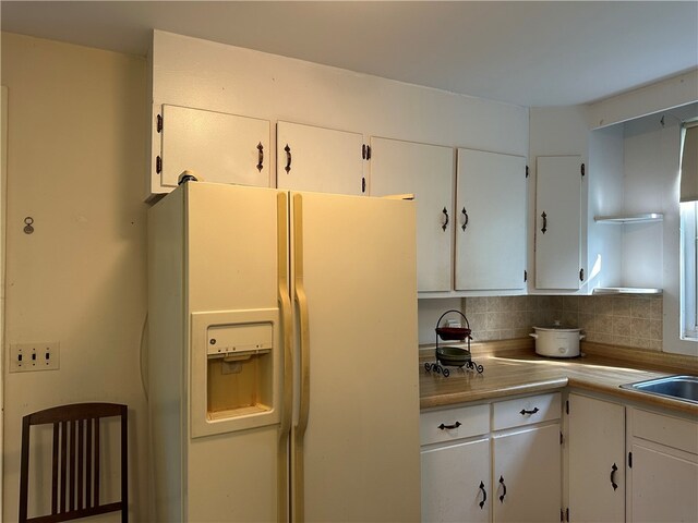 kitchen with white cabinetry, white refrigerator with ice dispenser, and tasteful backsplash