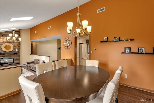 dining space featuring dark hardwood / wood-style flooring, baseboard heating, a chandelier, and a skylight