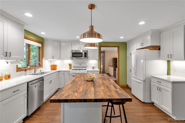 kitchen featuring a center island, light wood-type flooring, stainless steel appliances, sink, and butcher block counters