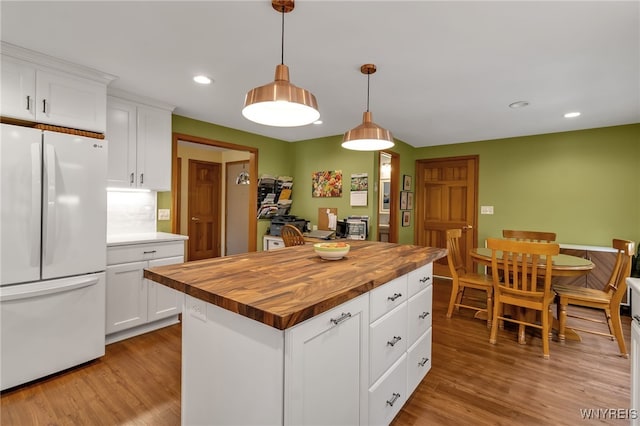 kitchen featuring white fridge, pendant lighting, light hardwood / wood-style floors, white cabinetry, and butcher block counters