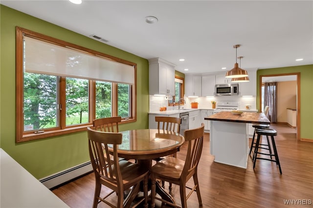 dining room featuring hardwood / wood-style flooring, baseboard heating, and sink