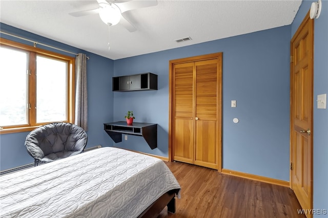 bedroom featuring a closet, ceiling fan, dark hardwood / wood-style flooring, and a textured ceiling