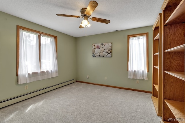 spare room with a baseboard heating unit, ceiling fan, light carpet, and a textured ceiling