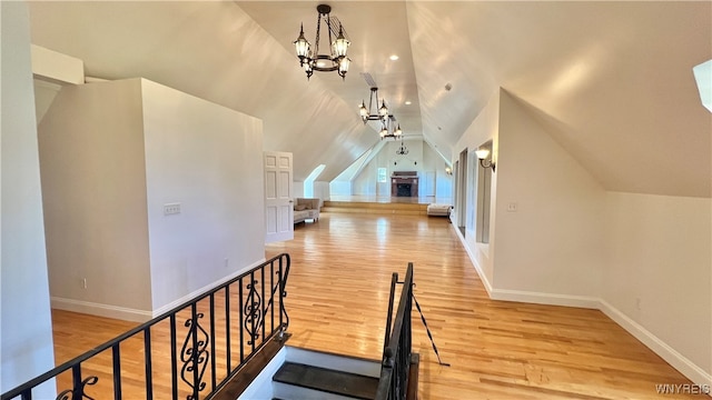 interior space featuring ceiling fan with notable chandelier, wood-type flooring, and lofted ceiling