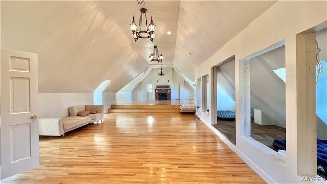 additional living space with lofted ceiling, light wood-type flooring, and a chandelier