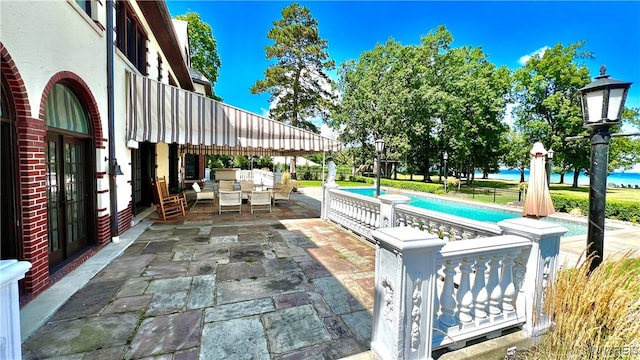 view of patio featuring area for grilling, a water view, and a pool