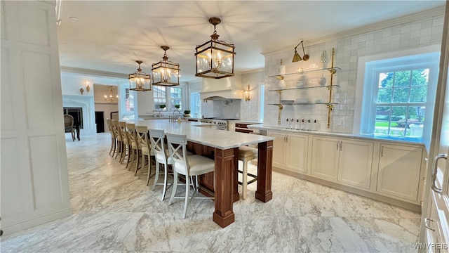 kitchen featuring backsplash, crown molding, stainless steel range, decorative light fixtures, and a kitchen bar