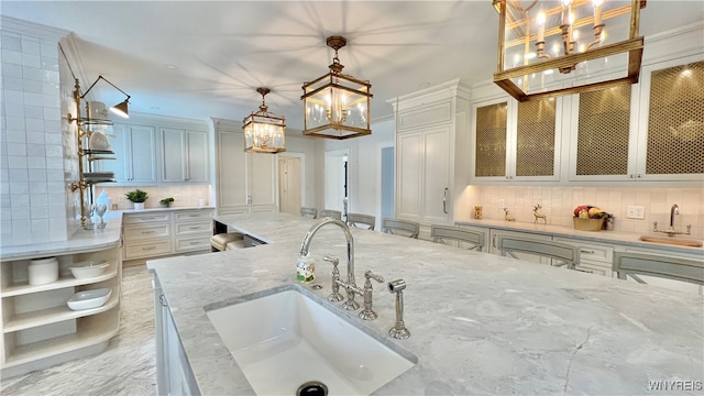 kitchen featuring pendant lighting, white cabinetry, and sink