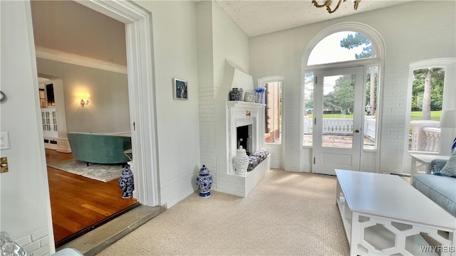 carpeted entrance foyer featuring a baseboard radiator, a textured ceiling, and a brick fireplace