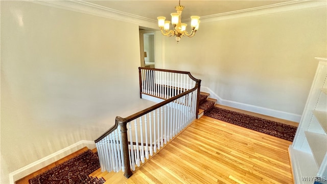 stairway with hardwood / wood-style flooring, ornamental molding, and a chandelier