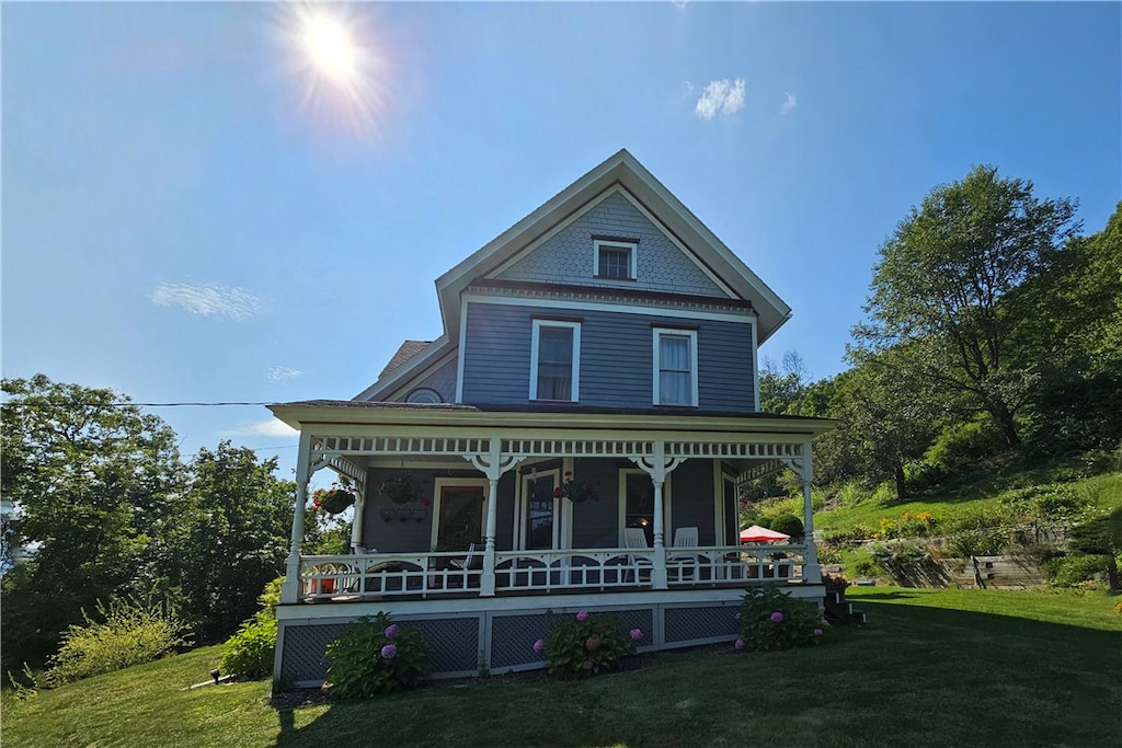 back of property with a lawn and covered porch