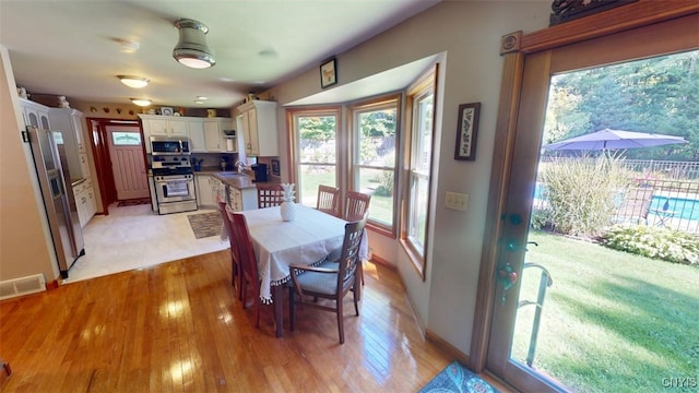 dining room featuring a healthy amount of sunlight, sink, and light hardwood / wood-style flooring