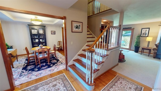 staircase with hardwood / wood-style flooring and a tray ceiling