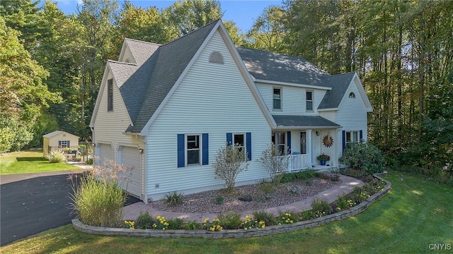 view of front facade featuring a porch, a garage, and a front lawn