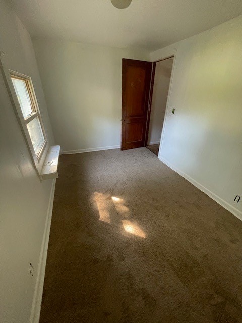 unfurnished room featuring dark colored carpet