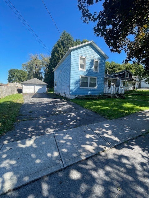 view of side of property featuring a garage, a yard, and an outbuilding