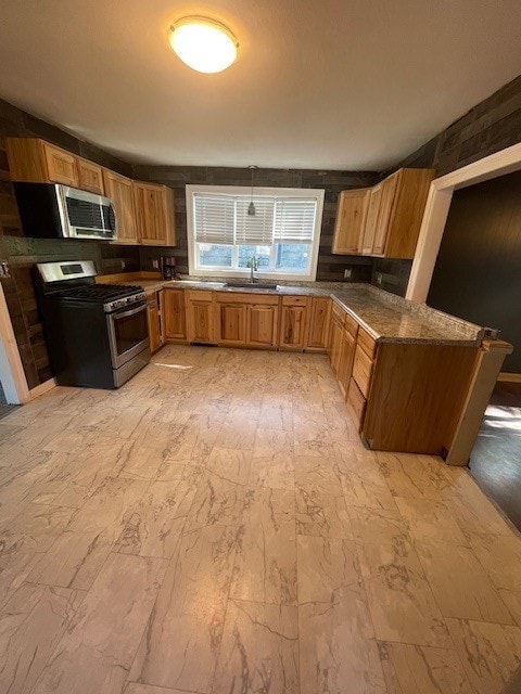 kitchen featuring dark stone countertops, appliances with stainless steel finishes, hanging light fixtures, and sink