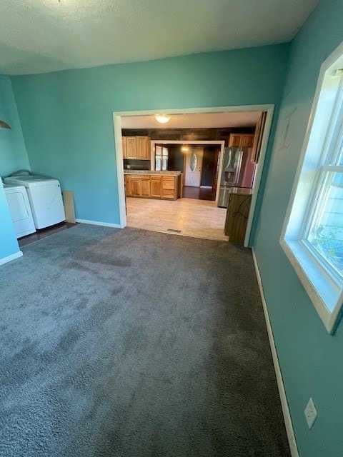 unfurnished living room featuring carpet floors, separate washer and dryer, and a textured ceiling