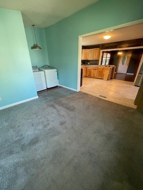 unfurnished living room with dark carpet and washing machine and dryer