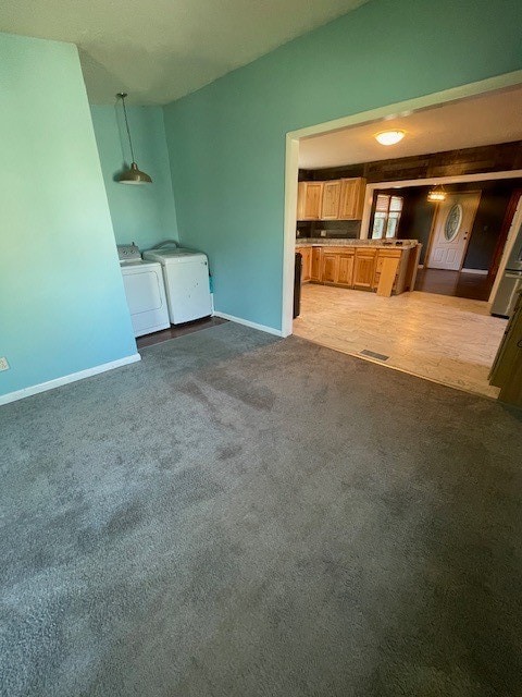 unfurnished living room featuring independent washer and dryer and carpet