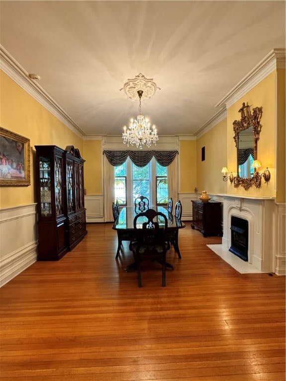 dining area with wood-type flooring, crown molding, and a notable chandelier