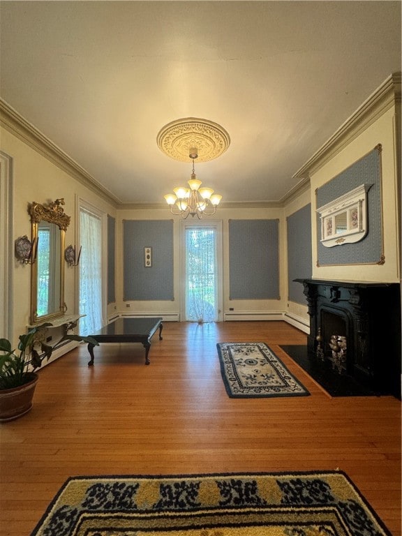 rec room featuring wood-type flooring, crown molding, baseboard heating, and an inviting chandelier