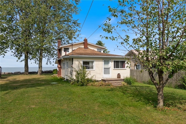 back of property with a water view and a yard