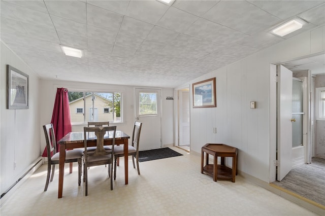 dining area with a baseboard heating unit and wood walls