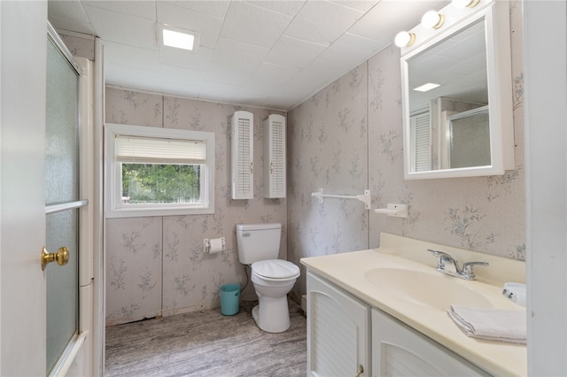 bathroom featuring vanity, toilet, hardwood / wood-style flooring, and a shower with shower door